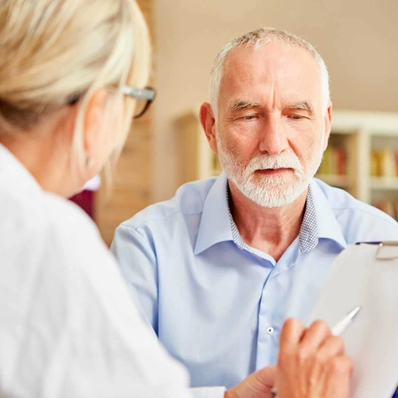 Onkologin berät älteren Patienten mit Fragebogen