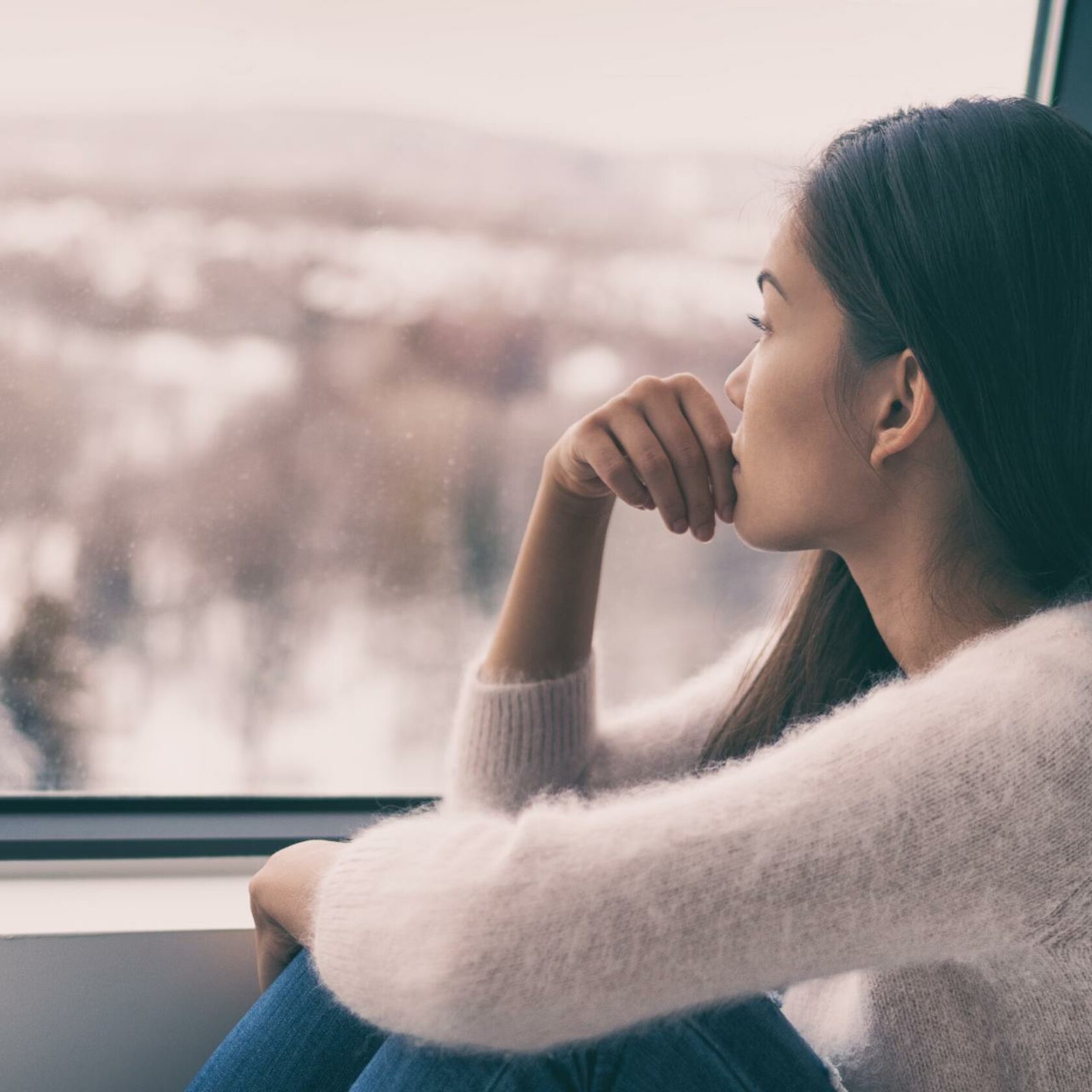Junge Frau sieht depressiv aus dem Fenster